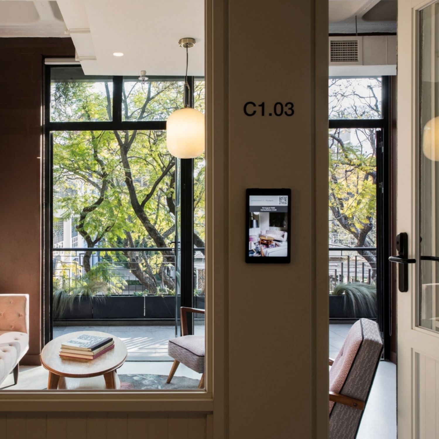 Meeting room in Hyde Johannesburg, with couches and chairs, and large opened glass doors that lead to the balcony.