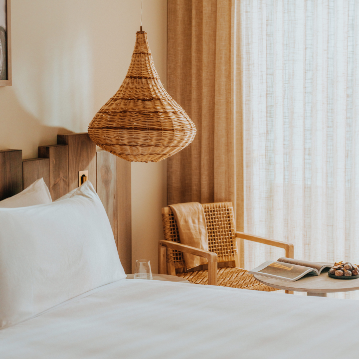 A king size bed with decorative light hanging from the ceiling, with an armchair next to the bed
