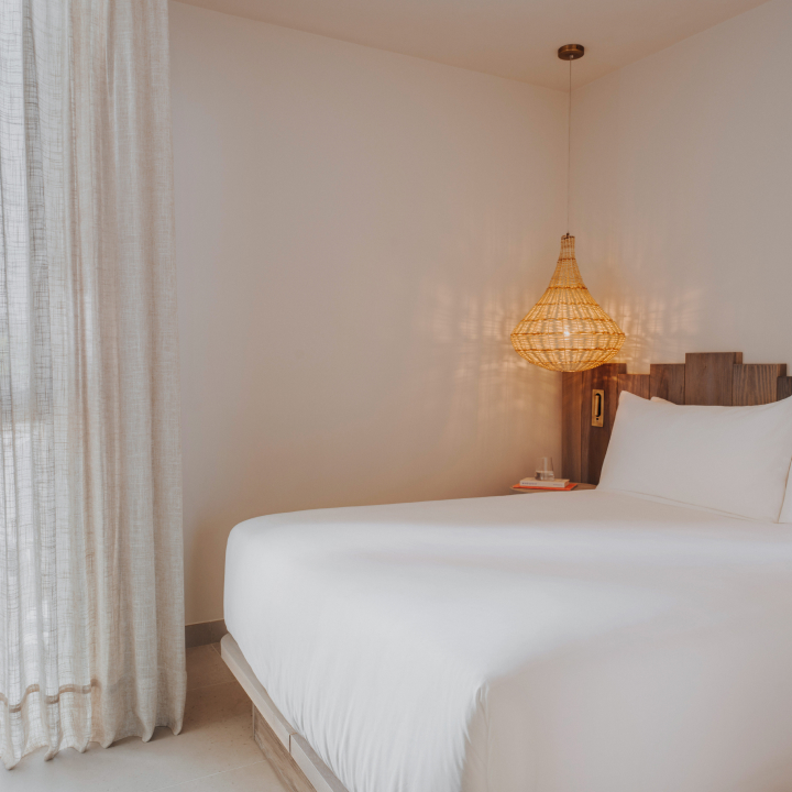A bedroom with white bedding and decorative light overhead