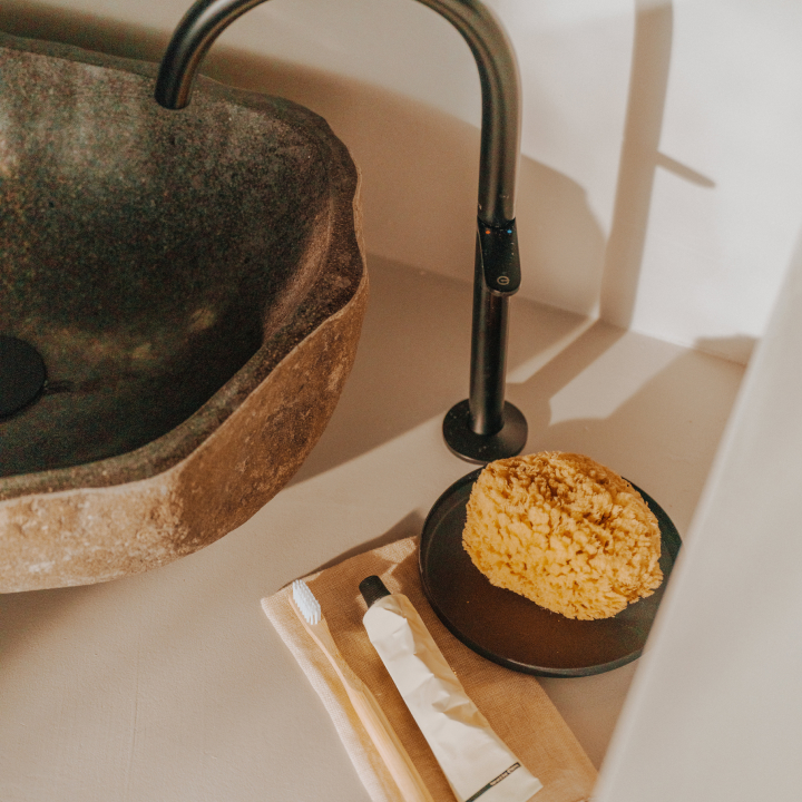 A sink and tap, with sponge, toothbrush and toothpaste alongside